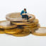 a miniature figurine of a person sitting on a stack of coins