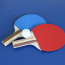 red and blue ping pong paddles and a white ball