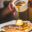 a person pouring syrup on a pancake
