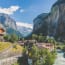 a river running through a valley with buildings and mountains