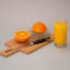 a knife and a cutting board with an orange and a glass of juice