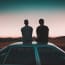 two people sitting on the roof of a car