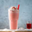 a glass of pink liquid on a wooden surface