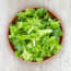 a bowl of lettuce on a wood surface