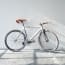 a white bicycle leaning against a white wall
