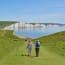 a group of people walking on a path with white cliffs in the background