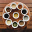 a group of small white cups with different sauces on a wooden table