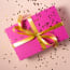 a pink box with a gold ribbon and a bow