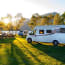 a group of RVs parked on grass next to a body of water