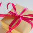a gift wrapped in brown paper with a pink ribbon