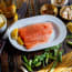 a plate of raw fish with lemon and herbs on a table