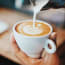 a person pouring milk into a cup of coffee