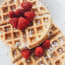 a waffle with raspberries and powdered sugar