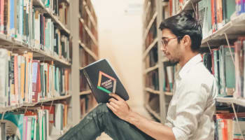 a person sitting in a library reading a book