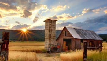 a barn with a tractor and silo in the background
