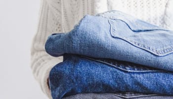 a stack of jeans on a white surface