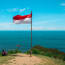 a person sitting on a hill with a flag on a pole