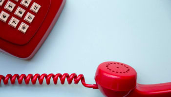 a red telephone receiver with a cord