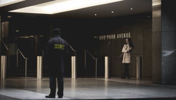 a person in a black coat and a person in a building