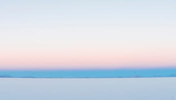 a snow covered land with mountains in the background