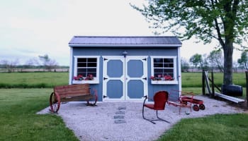 a small shed with a bench and chairs in front of it