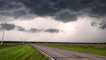 a road with grass and clouds above