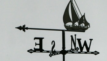 a weather vane with a sailboat and an arrow
