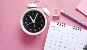a white alarm clock next to a calendar