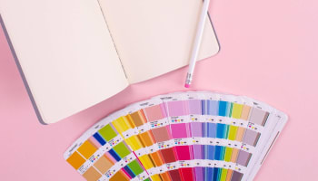 a book and pencil on a pink surface