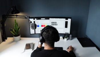 a person wearing headphones sitting at a desk with a computer