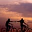 a silhouette of two people riding bicycles
