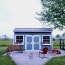 a small shed with a bench and chairs in front of it