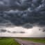 a road with grass and clouds above