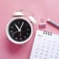 a white alarm clock next to a calendar