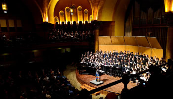 a group of people in a large room with a person on a stage