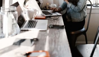 a person sitting at a desk with a laptop and a cup of coffee