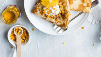 a plate of pancakes with orange slices and cream on top