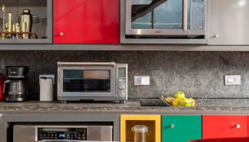 a kitchen counter with colorful cabinets and a microwave oven