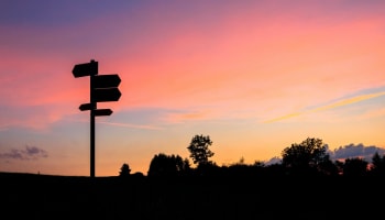 a sign post with a sunset in the background