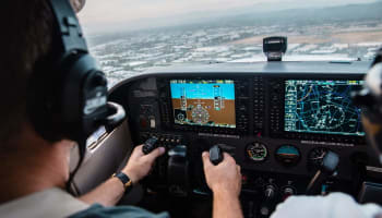 a person in a cockpit with a screen and buttons