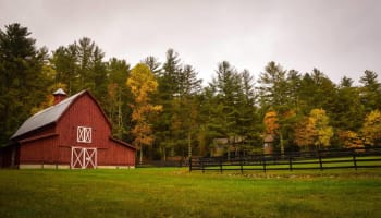 a red barn in a field with trees in the background