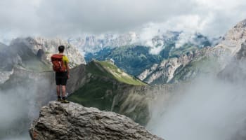 a person standing on a rock looking at mountains