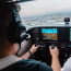 a person in a cockpit with a screen and buttons