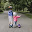 two children with helmets and scooters on a path