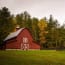 a red barn in a field with trees in the background