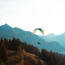 a person flying a parachute over a mountain