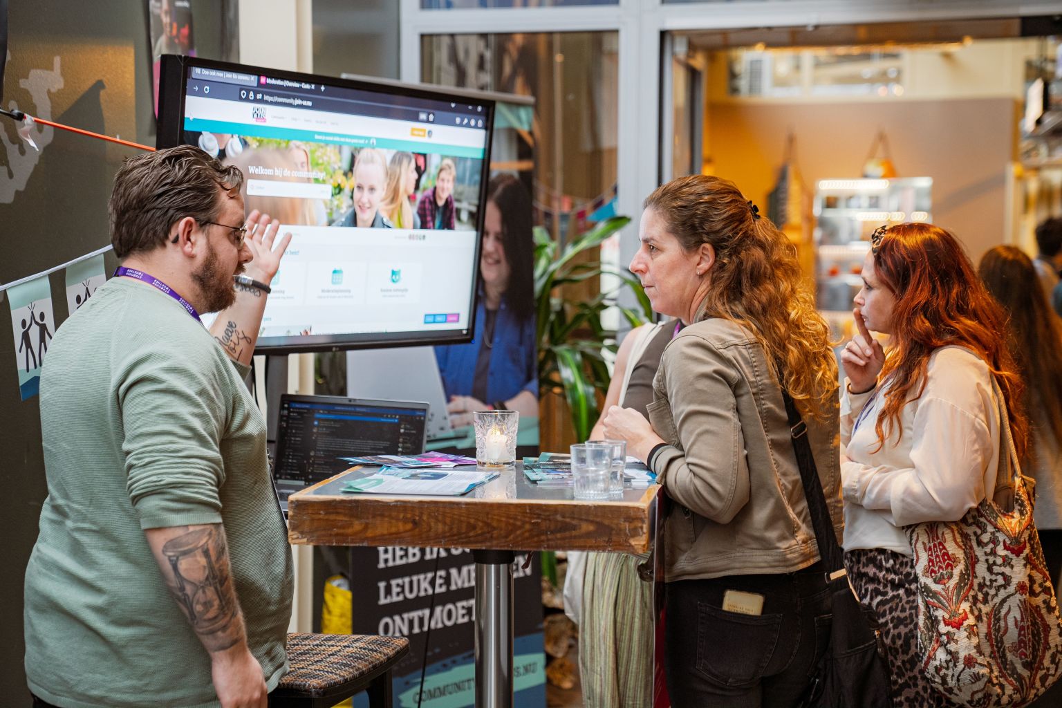 Join Us vrijwilliger die iets uitlegt aan een vrouw