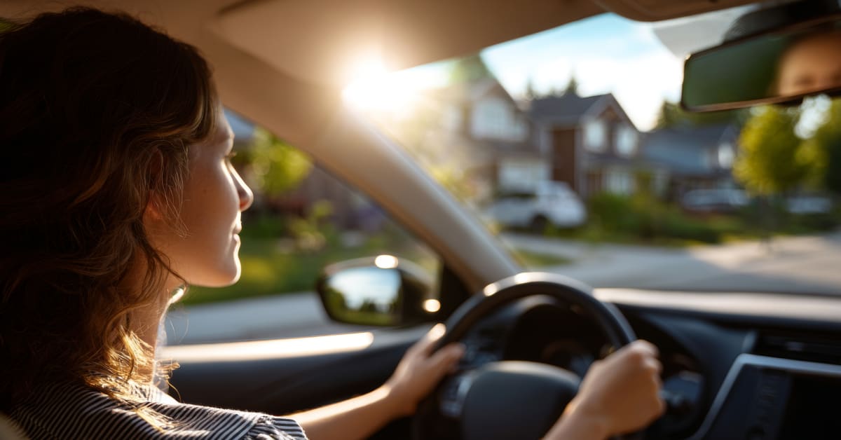 Woman driving her car through a neighborhood and smiling Woman driving her car through a neighborhood and smiling