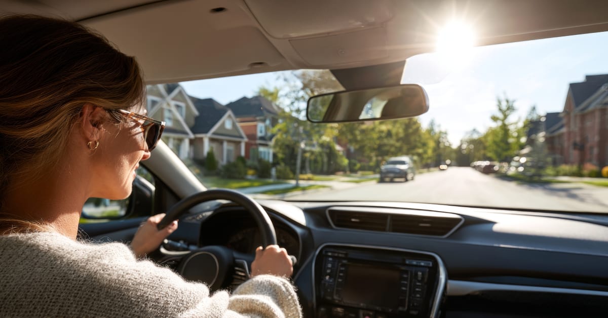 Woman with sunglasses driving car through neighborhood Woman with sunglasses driving car through neighborhood