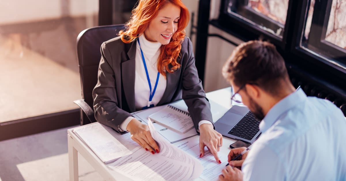 image of a woman at a desk sharing papers image of a woman at a desk sharing papers